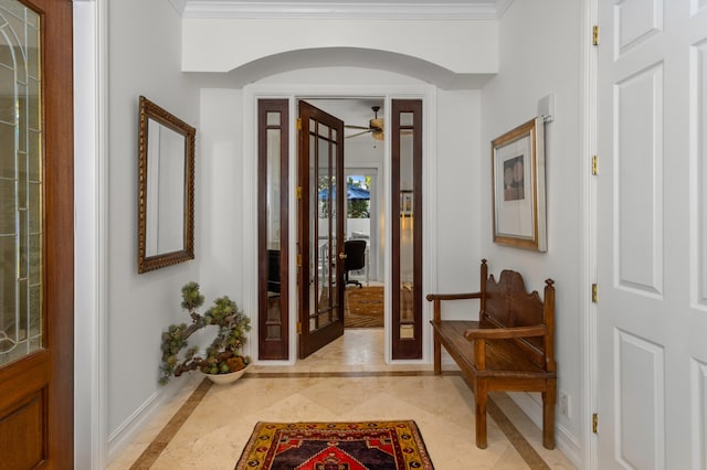 foyer entrance with baseboards, arched walkways, french doors, and ornamental molding