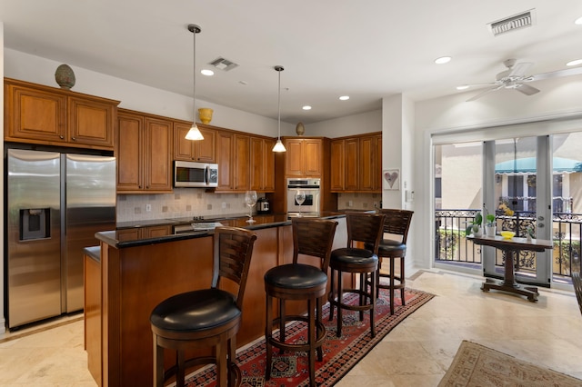 kitchen featuring decorative light fixtures, a center island, ceiling fan, a breakfast bar, and appliances with stainless steel finishes