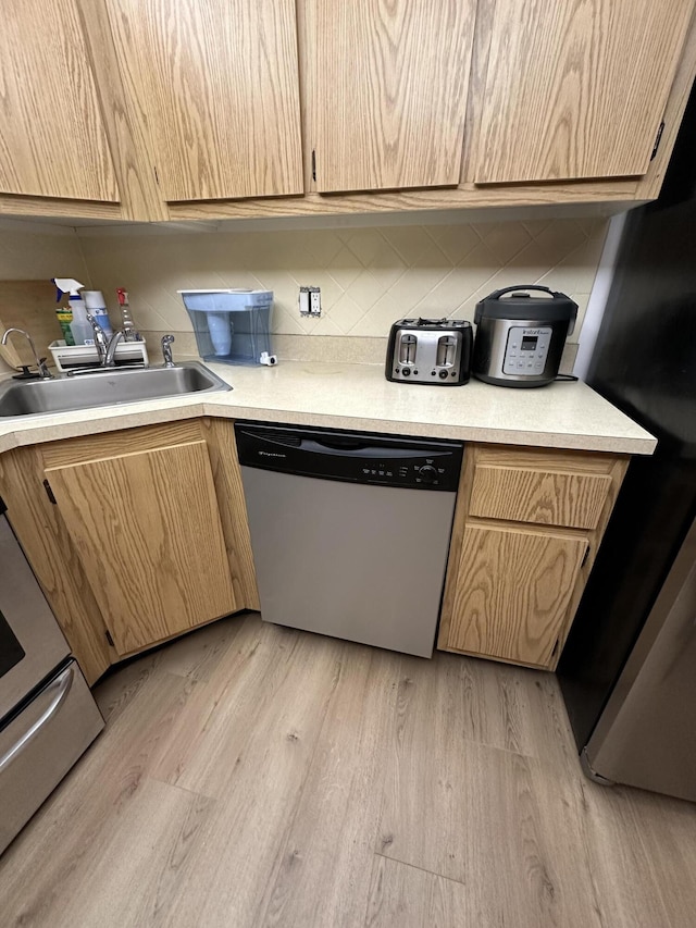 kitchen featuring tasteful backsplash, dishwasher, sink, and light hardwood / wood-style flooring