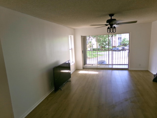 empty room with ceiling fan, wood-type flooring, and a textured ceiling