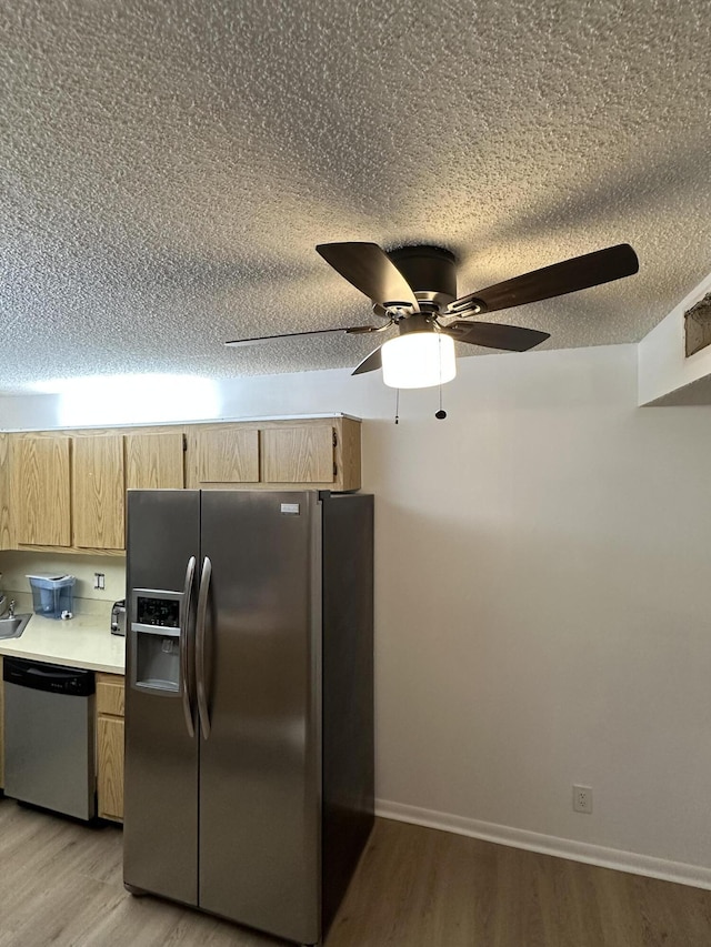 kitchen featuring stainless steel appliances, light brown cabinetry, light hardwood / wood-style floors, and a textured ceiling