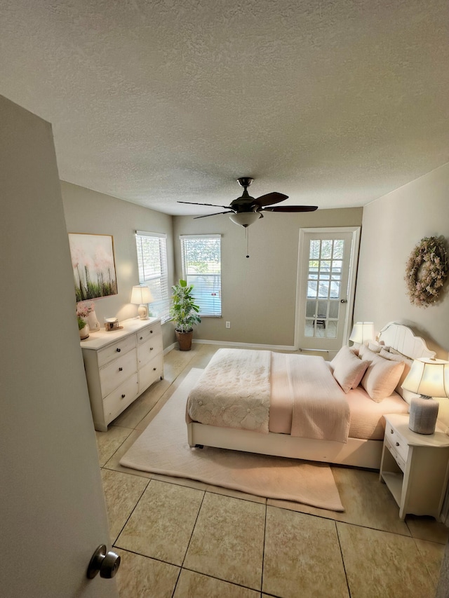 tiled bedroom with a textured ceiling, ceiling fan, and multiple windows