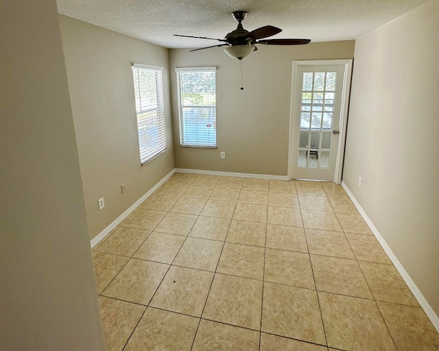 tiled empty room featuring a textured ceiling and ceiling fan