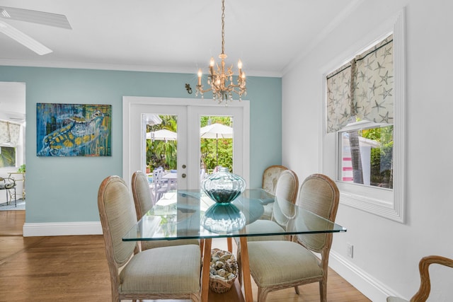 dining room featuring french doors, hardwood / wood-style floors, ceiling fan with notable chandelier, and ornamental molding