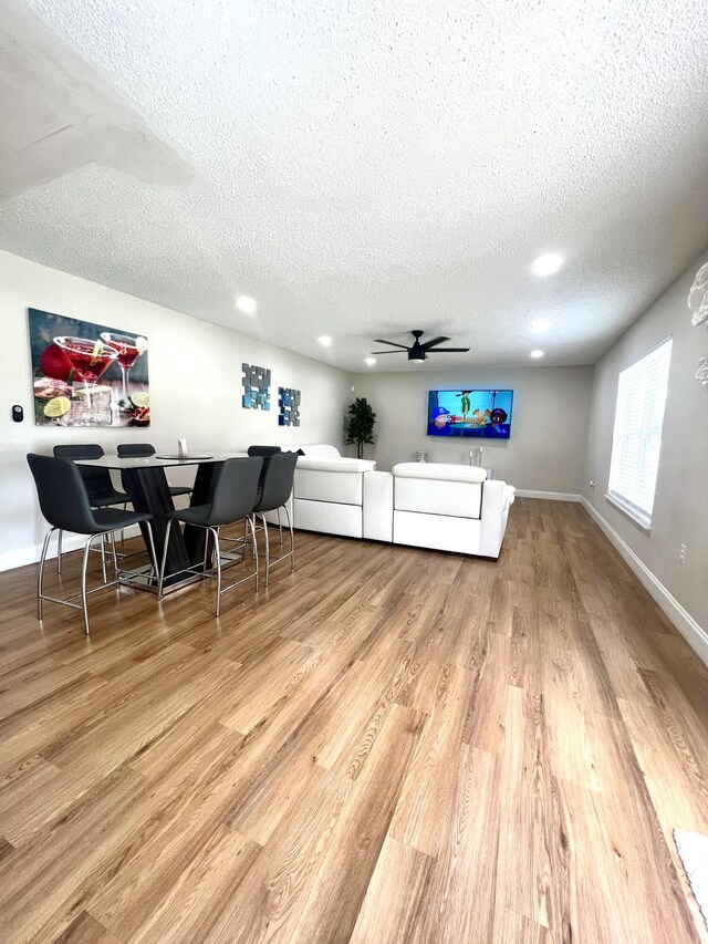 living room with a textured ceiling, hardwood / wood-style flooring, and ceiling fan