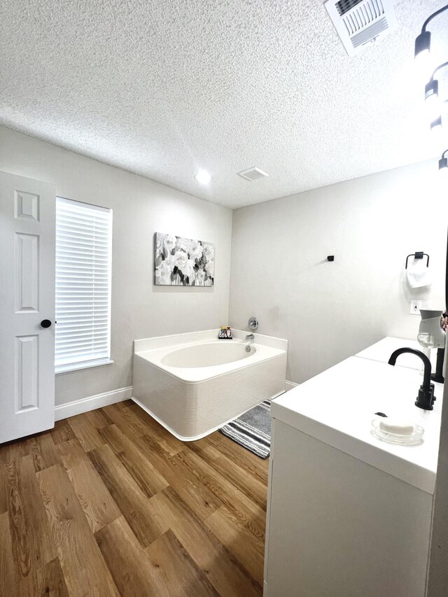 bathroom with a bathtub, vanity, a textured ceiling, and hardwood / wood-style flooring