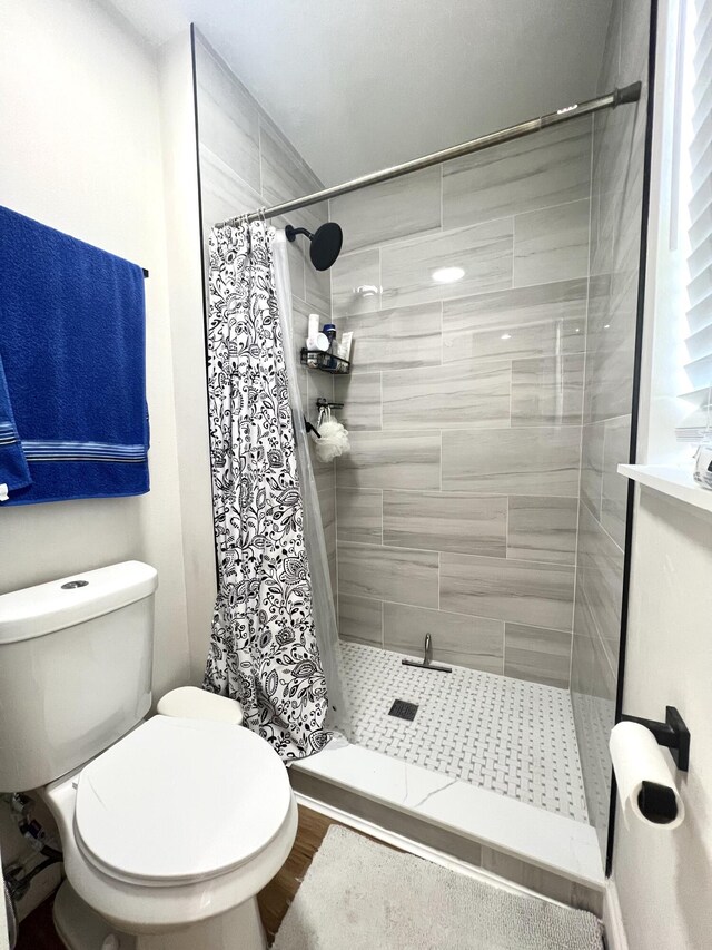 bathroom with a shower with shower curtain, wood-type flooring, and toilet