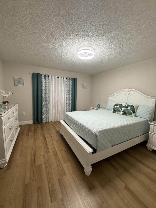 bedroom with light hardwood / wood-style floors and a textured ceiling