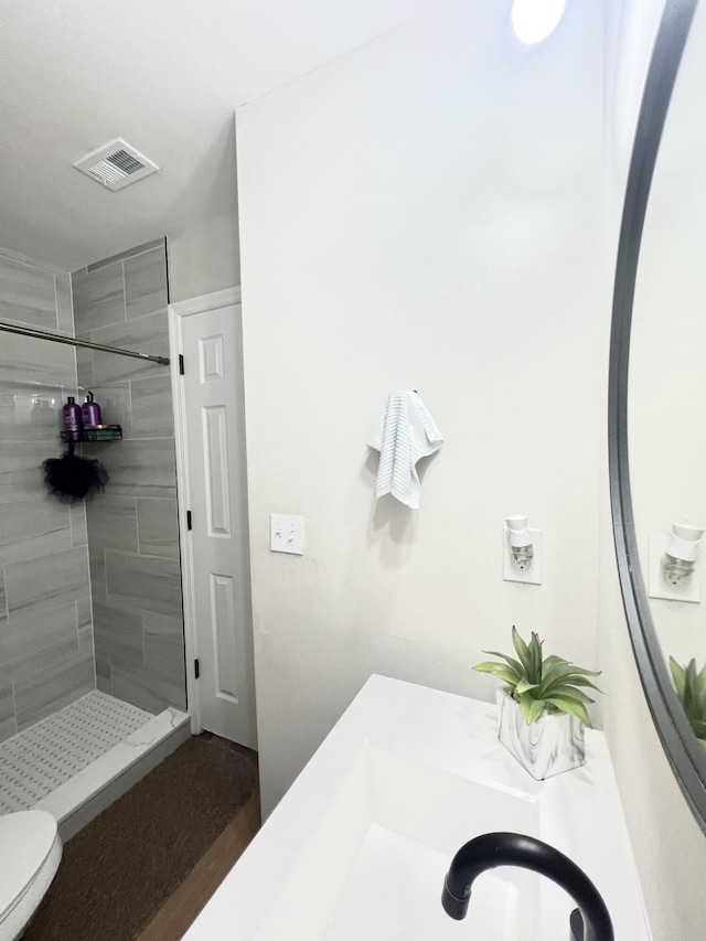 bathroom with tiled shower and toilet