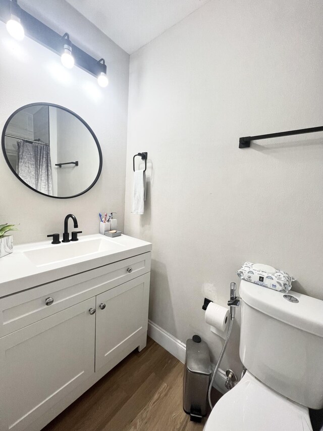 bathroom with hardwood / wood-style floors, vanity, and toilet