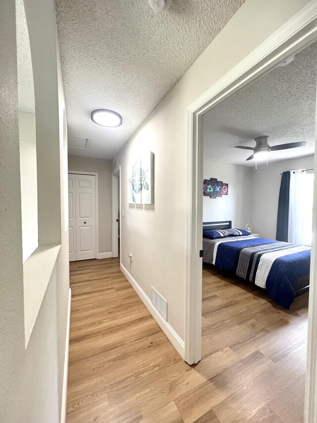 hallway featuring light hardwood / wood-style floors and a textured ceiling