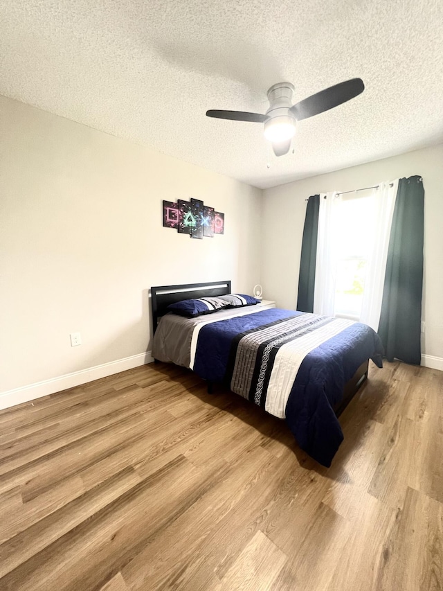 bedroom featuring ceiling fan, light hardwood / wood-style flooring, and a textured ceiling