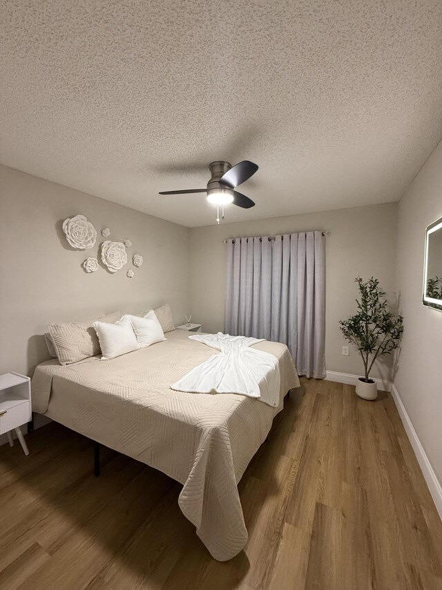 bedroom featuring ceiling fan, light hardwood / wood-style flooring, and a textured ceiling