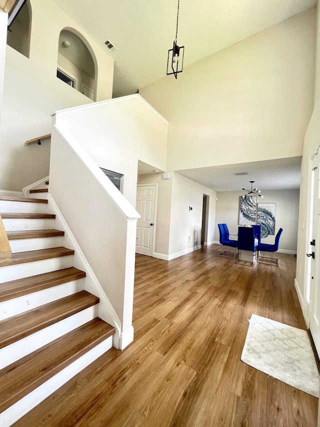 entryway featuring a notable chandelier, wood-type flooring, and a high ceiling