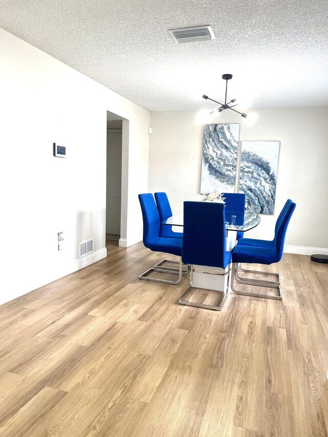 dining space with light hardwood / wood-style floors and a textured ceiling