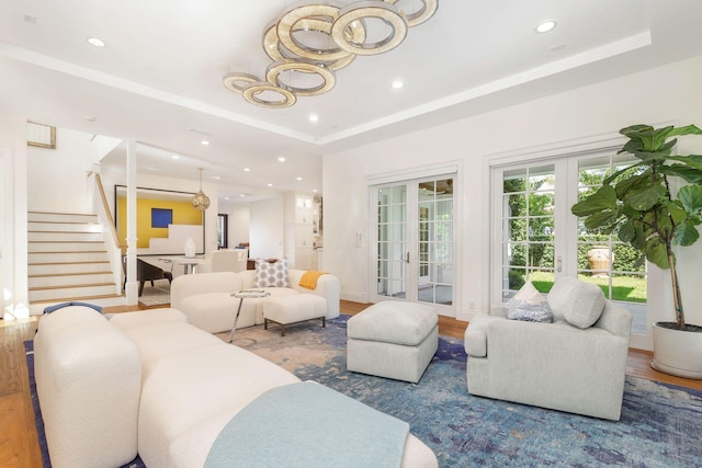 living room featuring a tray ceiling, french doors, and wood-type flooring