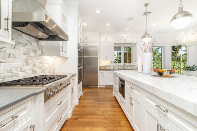 kitchen with white cabinets, a wealth of natural light, stainless steel appliances, and wall chimney exhaust hood