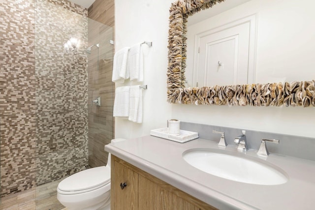 bathroom featuring tiled shower, vanity, and toilet