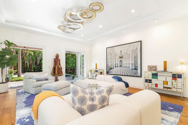 living room featuring a tray ceiling, light hardwood / wood-style flooring, and a notable chandelier