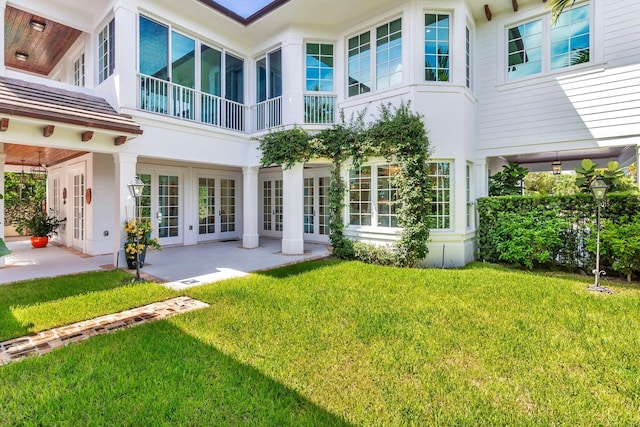 back of property with a balcony, a patio area, and a yard