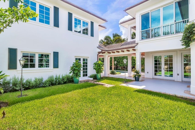 rear view of property featuring french doors, a patio area, and a yard