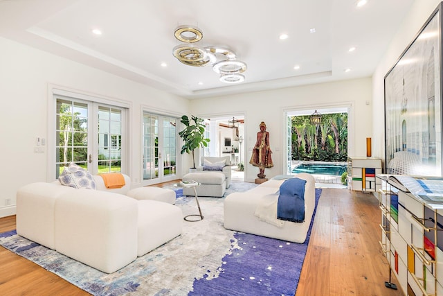 living room featuring a raised ceiling, french doors, and light hardwood / wood-style floors