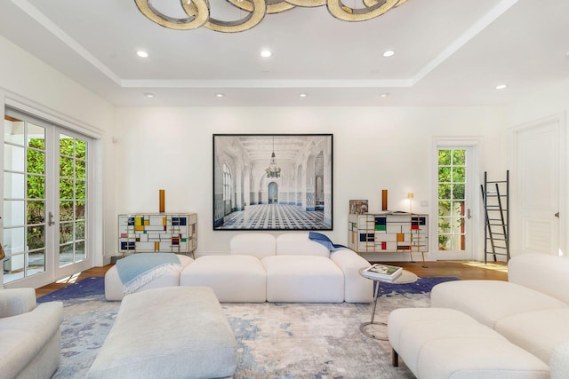 living room featuring light wood-type flooring, a wealth of natural light, a raised ceiling, and french doors