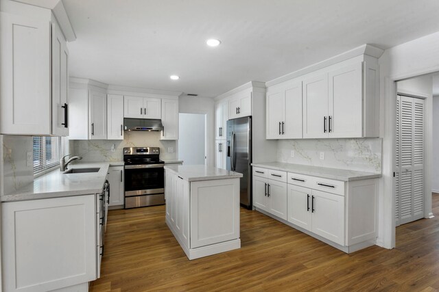 kitchen featuring appliances with stainless steel finishes, white cabinetry, wood-type flooring, and a kitchen island