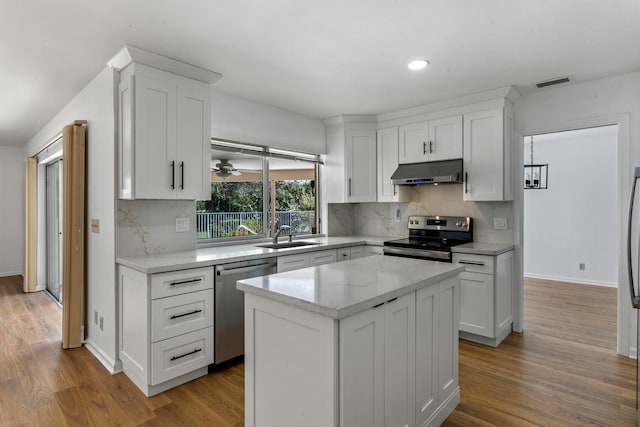 kitchen with a kitchen island, stainless steel appliances, light hardwood / wood-style flooring, and white cabinets