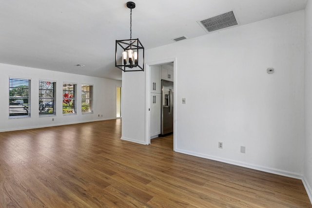 unfurnished living room with hardwood / wood-style floors and a chandelier