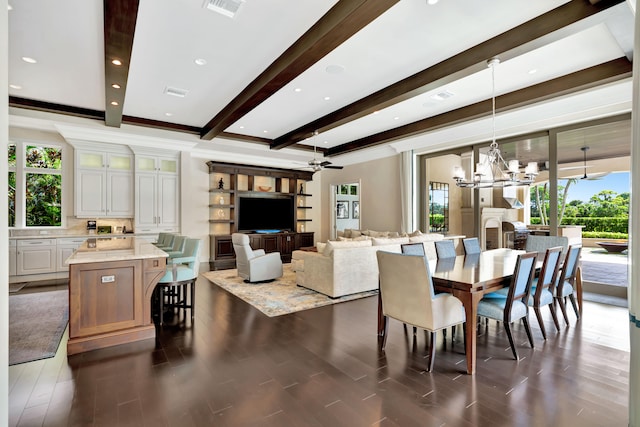 dining room with ceiling fan with notable chandelier, beamed ceiling, a fireplace, and dark hardwood / wood-style floors