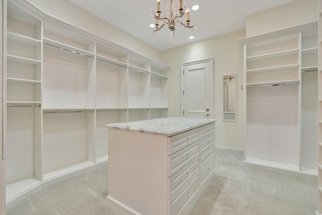 walk in closet with an inviting chandelier and light carpet