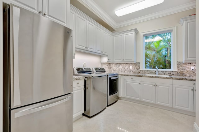 kitchen with light stone countertops, separate washer and dryer, stainless steel refrigerator, sink, and white cabinets