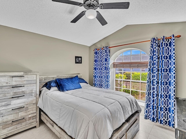 bedroom featuring ceiling fan, light tile patterned floors, a textured ceiling, and vaulted ceiling