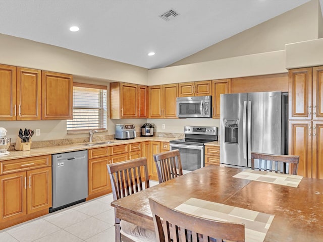 kitchen featuring lofted ceiling, appliances with stainless steel finishes, light tile patterned floors, and sink