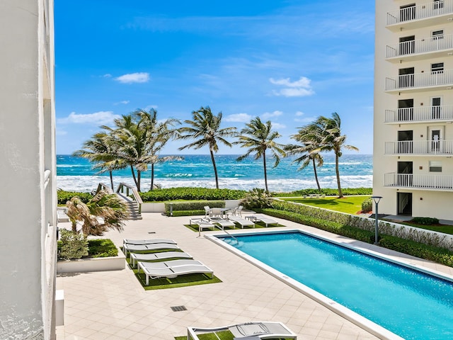 view of pool with a beach view, a patio area, and a water view