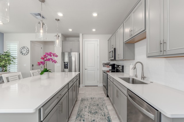 kitchen featuring a large island, stainless steel appliances, gray cabinetry, and sink