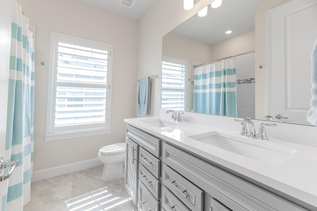 bathroom with tile patterned flooring, plenty of natural light, vanity, and toilet