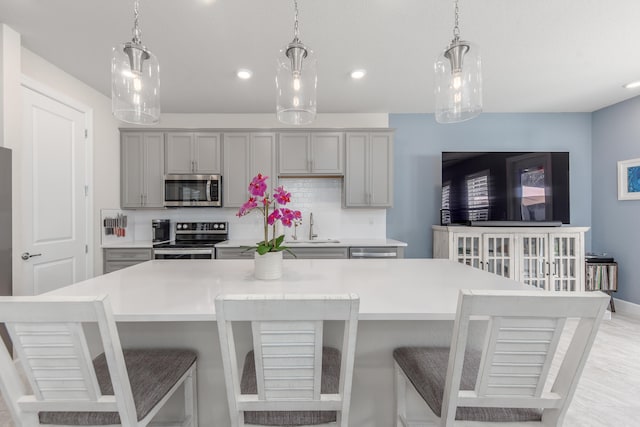 kitchen featuring gray cabinets, stainless steel appliances, a kitchen breakfast bar, and a large island with sink