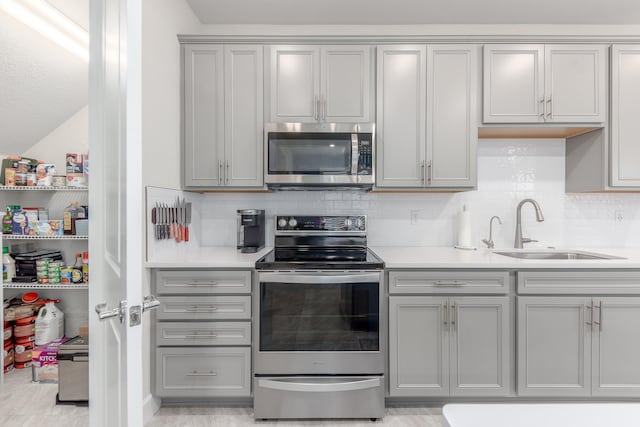 kitchen featuring appliances with stainless steel finishes, decorative backsplash, sink, and gray cabinets