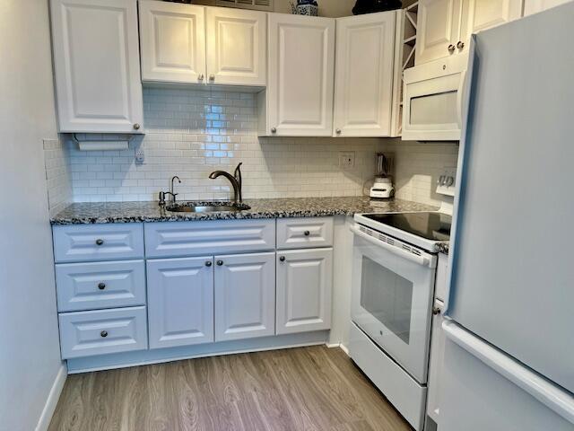 kitchen featuring white cabinetry, sink, white appliances, and light hardwood / wood-style floors