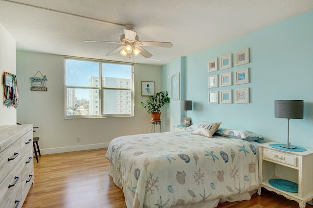 bedroom with light wood-type flooring, a textured ceiling, and ceiling fan