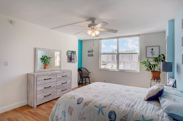 bedroom featuring light wood-type flooring, ceiling fan, and a textured ceiling