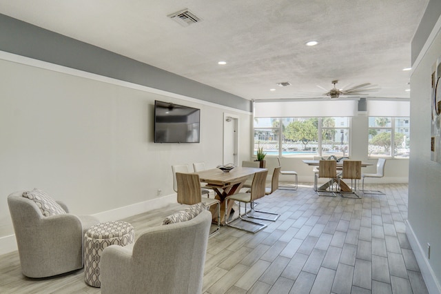 dining space with ceiling fan, a textured ceiling, and light hardwood / wood-style floors