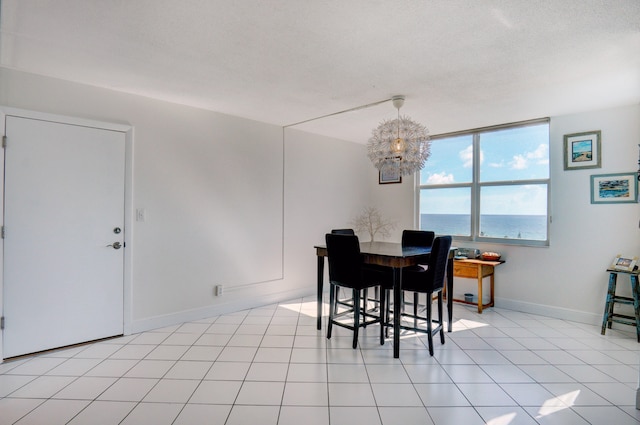 dining room with a notable chandelier, a textured ceiling, light tile patterned floors, and a water view