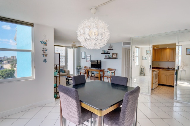 tiled dining room featuring ceiling fan with notable chandelier, sink, and a healthy amount of sunlight