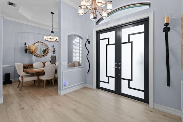 foyer featuring crown molding, french doors, a notable chandelier, and light hardwood / wood-style floors