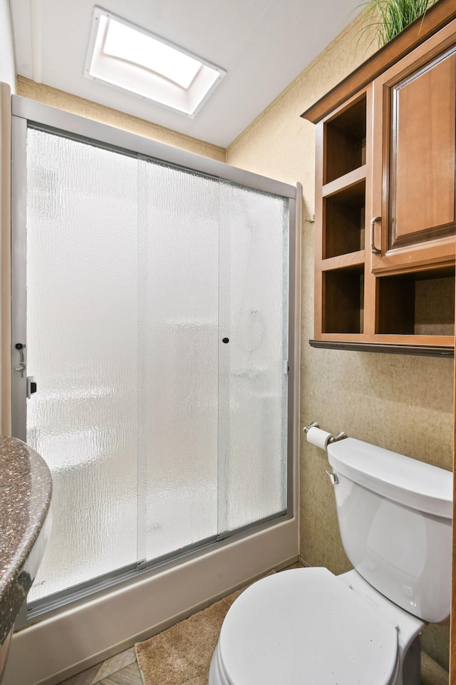 bathroom with an enclosed shower, a skylight, and toilet