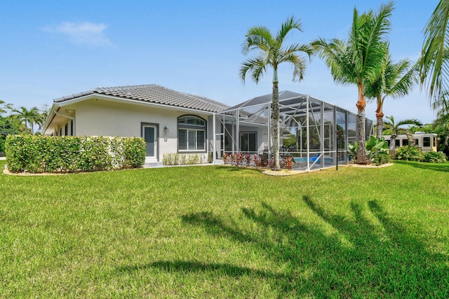 rear view of property featuring a lanai and a lawn