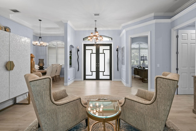 living area featuring light hardwood / wood-style flooring, ornamental molding, and an inviting chandelier